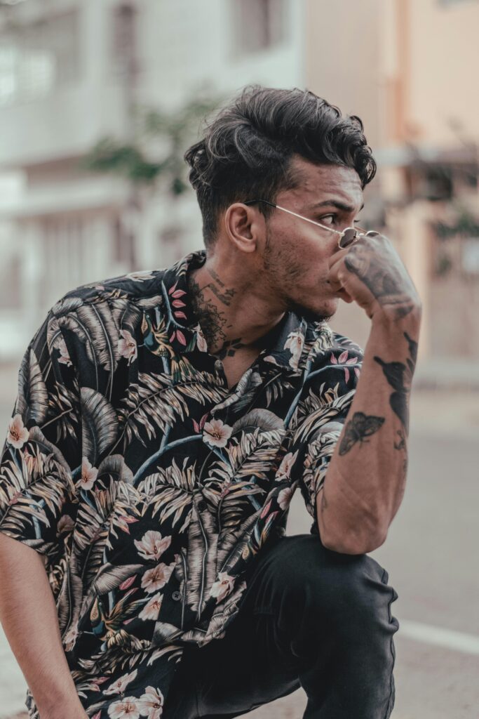 Urban style meets fashion as man in floral shirt poses thoughtfully.