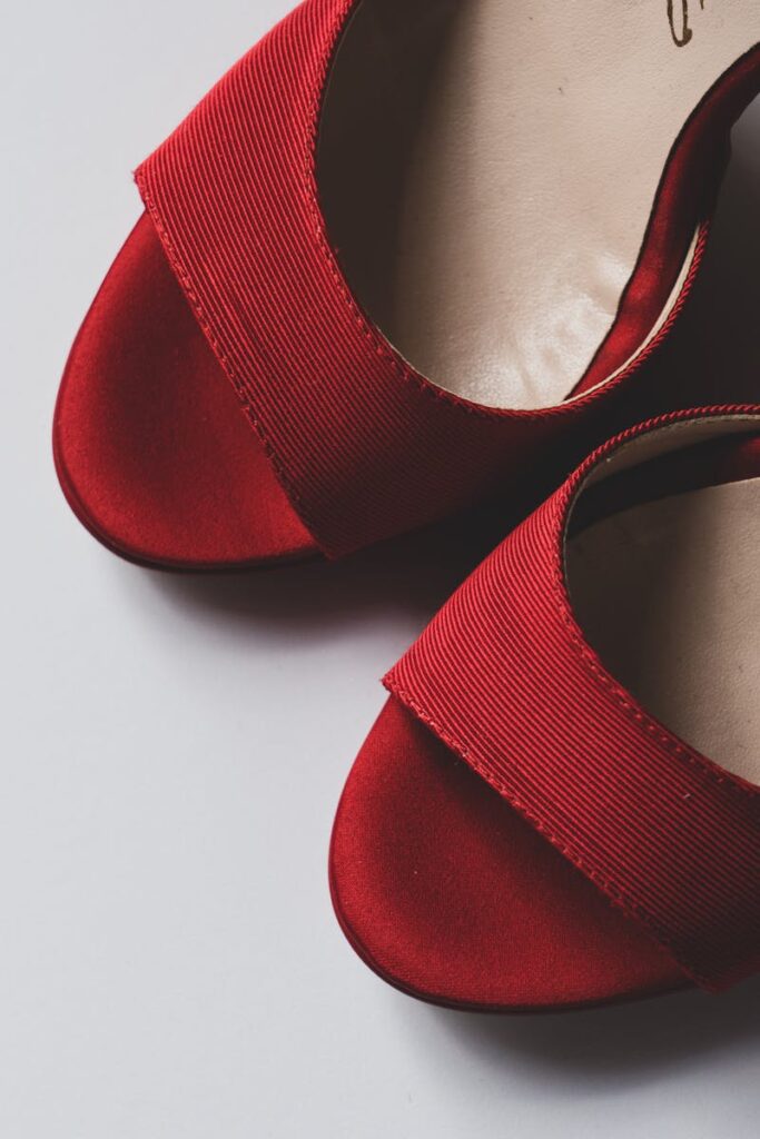 Stylish red high-heeled shoes on a white surface, perfect for fashion and romantic themes.