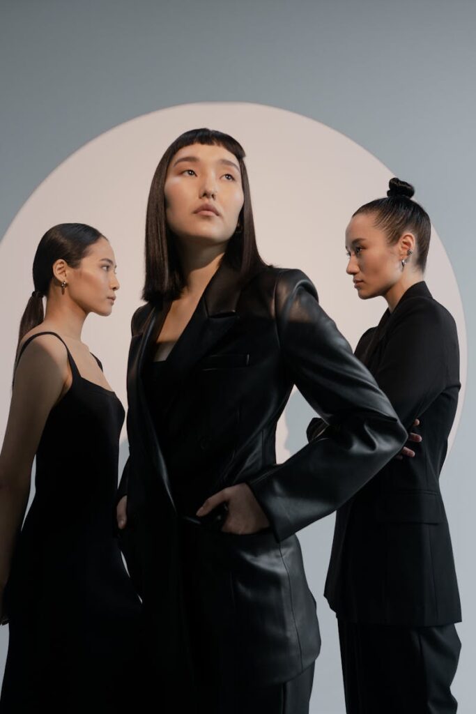 Group of Asian women in black outfits posing in a modern studio.